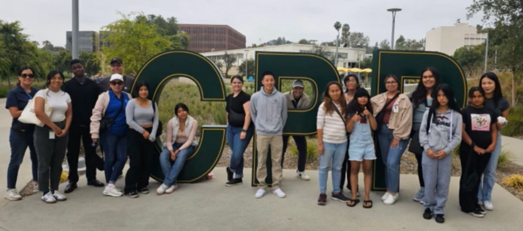 Group of people standing in front of the Cal Poly Pomona sign